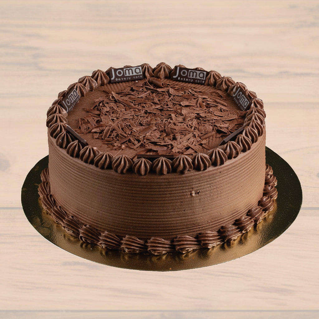 A chocolate cake with chocolate frosting and decorative chocolate shavings on top, placed on a golden round plate with the brand name 'Jome' visible on the side.