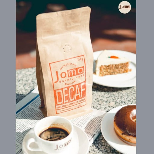 Joma coffee bag with a cup of coffee and donut on a table