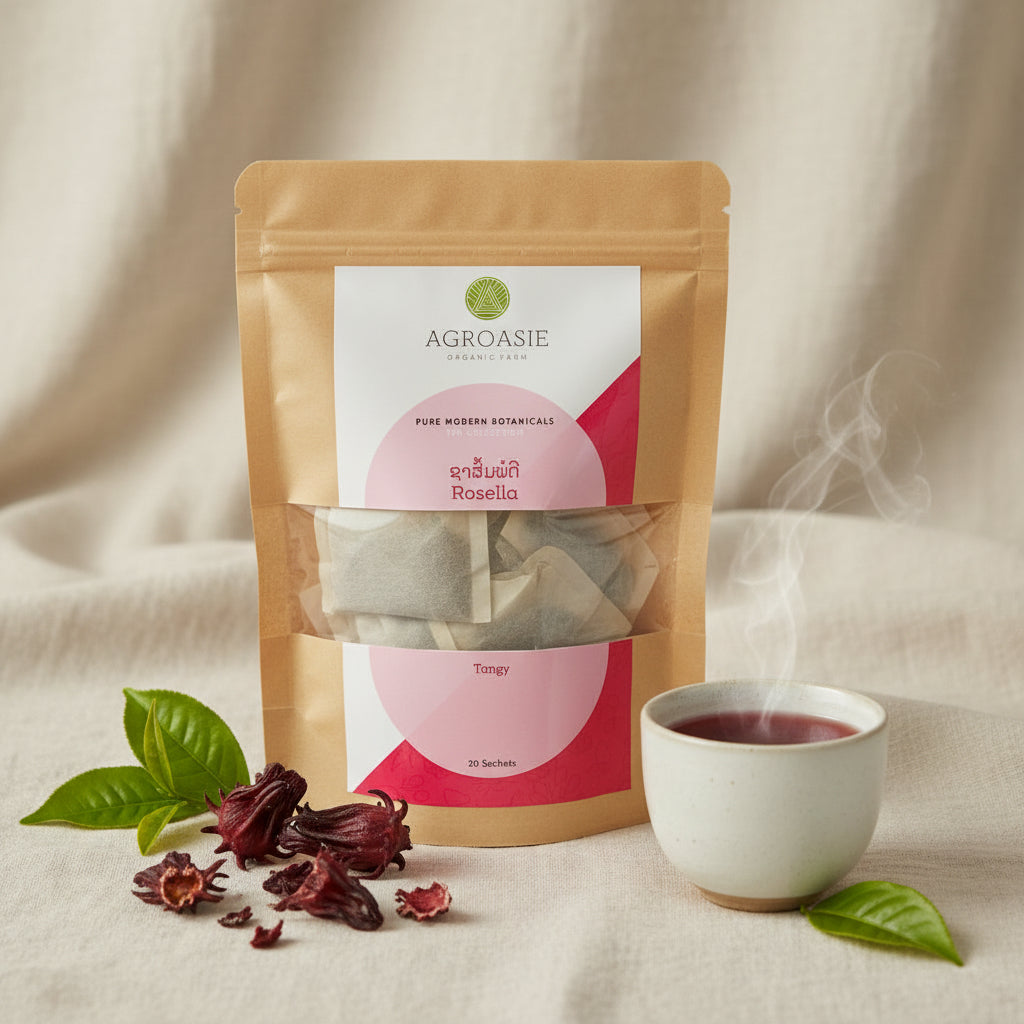 A kraft paper stand-up pouch of AGROASIE Rosella Tangy herbal tea sachets, showing the tea inside through a clear window on a white background.