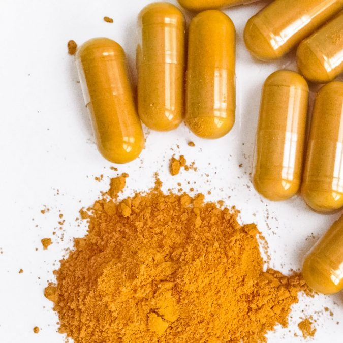 Yellow capsules and powder on a white background
