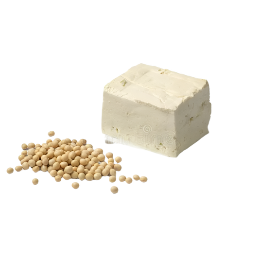 A block of fresh white tofu next to a small pile of cooked yellow peas on a white plate, isolated on a white background.
